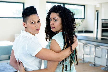 Lesbian couple embracing and looking at cameraの写真素材