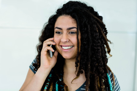 Woman smiling while talking on mobile phoneの写真素材