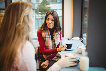 Pretty friends chatting over coffee in cafeの写真素材