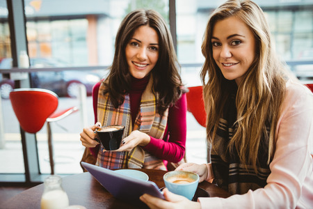 Friends using tablet together in cafeの写真素材