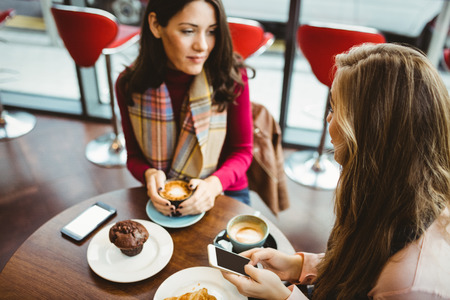 Friends using their smartphone in cafeの写真素材