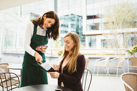 Smiling waitress taking an order in cafeの写真素材
