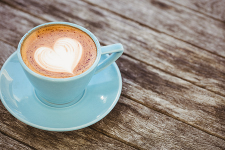 Cup of cappuccino with coffee art on wooden table at coffee shopの写真素材