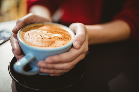 Woman holding a cup of coffee in a cafeの写真素材