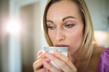 Pretty blonde woman having coffee at home