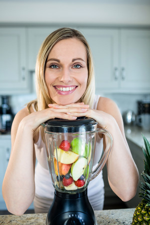 Pretty blonde woman preparing a smoothie in the kitchenの写真素材