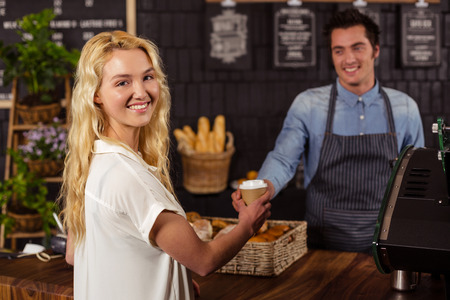 Smiling waiter serving a coffee to a customer at the cafe