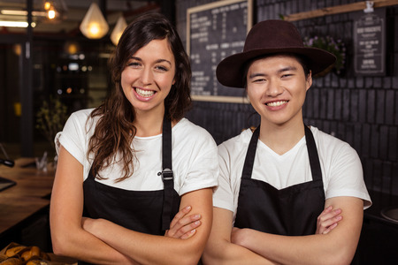 Smiling co-workers posing with crossed arms at the coffee shopの写真素材