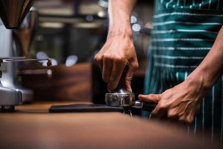 Waiter squeezing the coffee in the percolator at the coffee shopの写真素材
