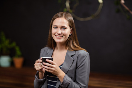 Smiling woman holding a cup of coffee in a cafe