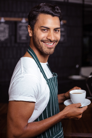 Smiling barista holding coffee in the barの写真素材