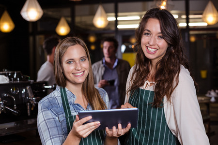 Pretty baristas using tablet in the barの写真素材