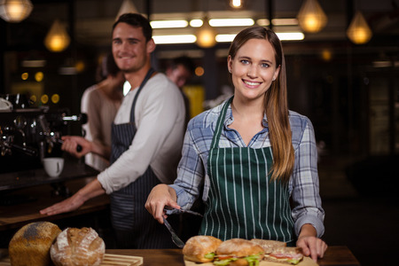 Pretty barista smiling at camera at the cafe