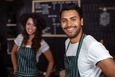 Smiling baristas looking at the camera in the barの写真素材