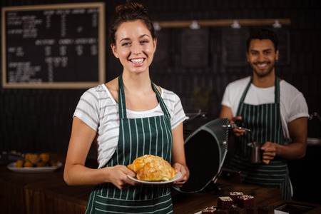 Smiling barista holding croissants in the barの写真素材