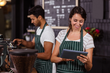 Smiling barista using tablet in the barの写真素材