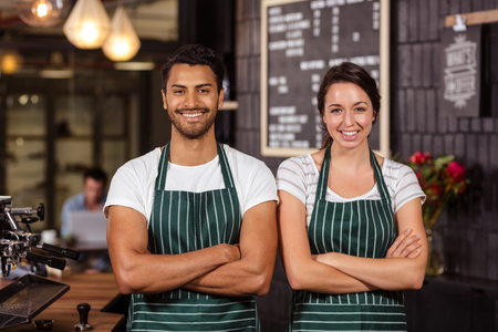 Smiling baristas standing with arms crossed and looking at the cameraの写真素材