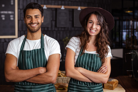 Smiling baristas standing with arms crossed in the barの写真素材