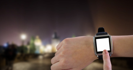 Smartwatch on wrist against cityscape by nightの写真素材