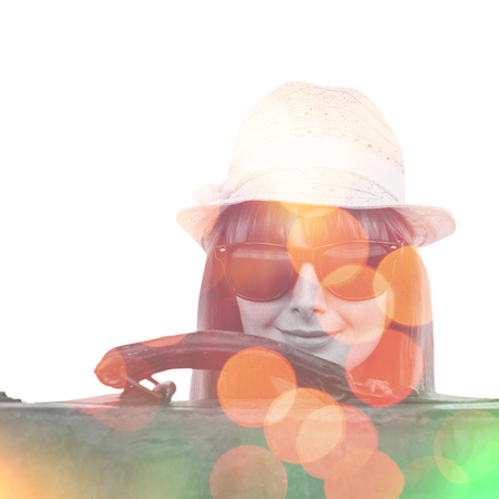 Smiling hipster woman behind a suitcase against background of multiple colorの写真素材