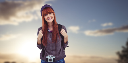 Portrait of a smiling hipster woman with a retro camera against sunset over a fieldの写真素材