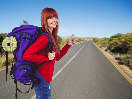Smiling hipster woman with a travel bag against picture of a streetの写真素材
