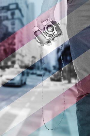 Close up view of man hand holding retro photo camera  against colored background