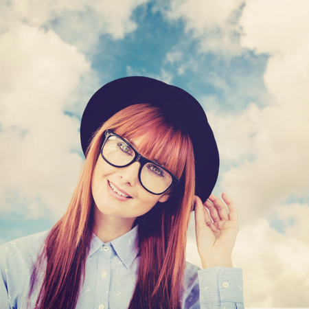Smiling hipster woman posing face to the camera against blue sky with white cloudsの写真素材