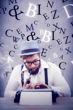 Hipster smoking pipe while working at desk against white and grey backgroundの写真素材