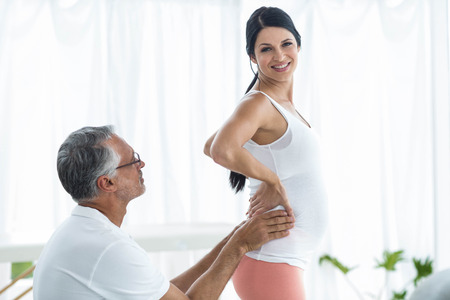 Doctor examining and giving physiotherapy to pregnant woman on exercise ballの写真素材