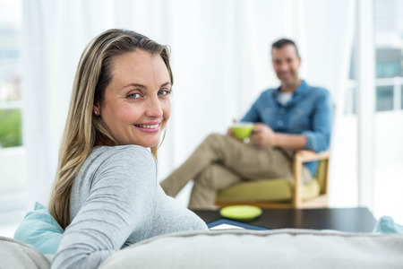 Pregnant woman sitting on sofa in living roomの写真素材