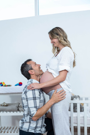 Portrait of man touching the belly of pregnant woman at homeの写真素材