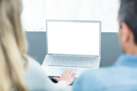 Couple sitting on sofa and using laptop in living room