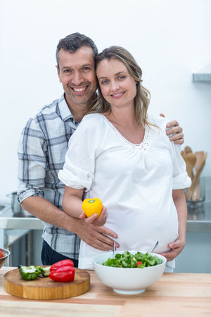 Portrait of pregnant couple looking at camera in kitchenの写真素材