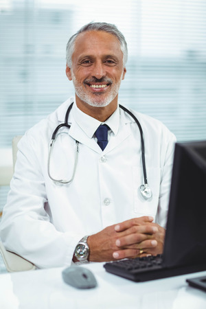 Portrait of doctor working on his computer in cabinの写真素材
