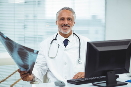 Portrait of happy doctor holding x-ray in clinicの写真素材