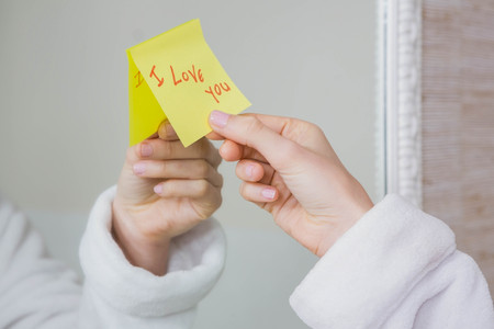 Woman sticking I love you word sticky note on mirrorの写真素材
