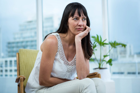 Pregnant woman sitting depressed at homeの写真素材