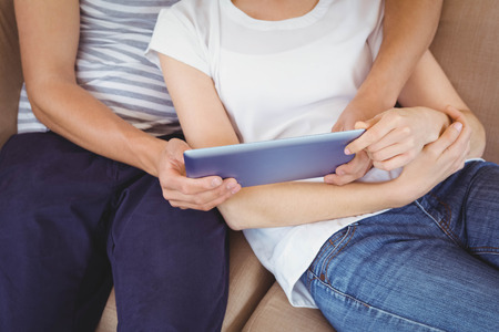 Young couple relaxing on sofa and using digital tablet in living roomの写真素材