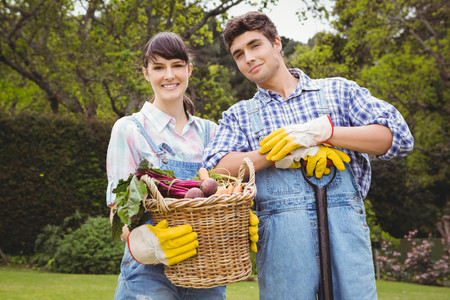Young couple holding a basket of freshly harvested vegetables in gardenの写真素材