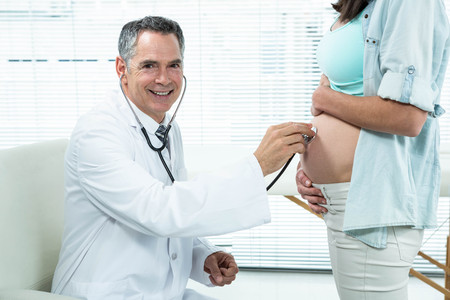 Doctor examining a pregnant woman in hospitalの写真素材