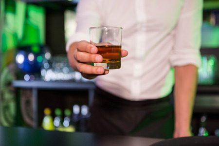 Bartender serving a glass of whiskey in barの写真素材