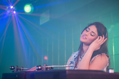 Pretty female DJ playing music at the nightclubの写真素材