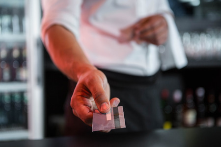 Bartender accepting a credit card at bar counter in barの写真素材