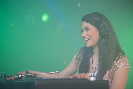 Pretty female DJ playing music at the nightclub