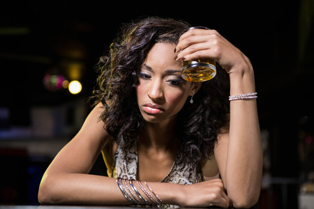 Depressed woman having whiskey drink at bar counter in barの写真素材