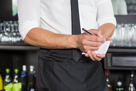 Waiter writing down an order in a barの写真素材