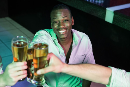 Happy man toasting his glass of beer with friends in barの写真素材