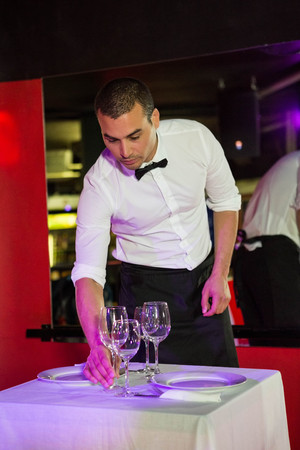 Waiter setting a table in a bar