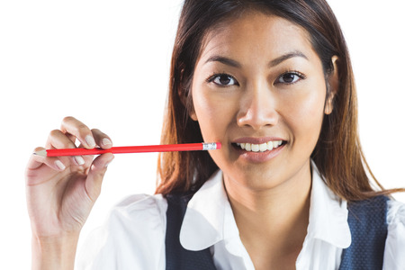 Smiling businesswoman holding a pencil on white backgroundの写真素材